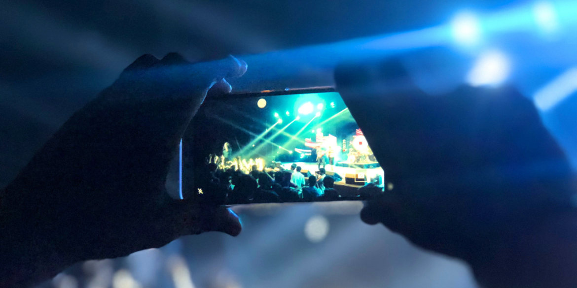 Een persoon die eenmet een telefoon filmt bij een concert